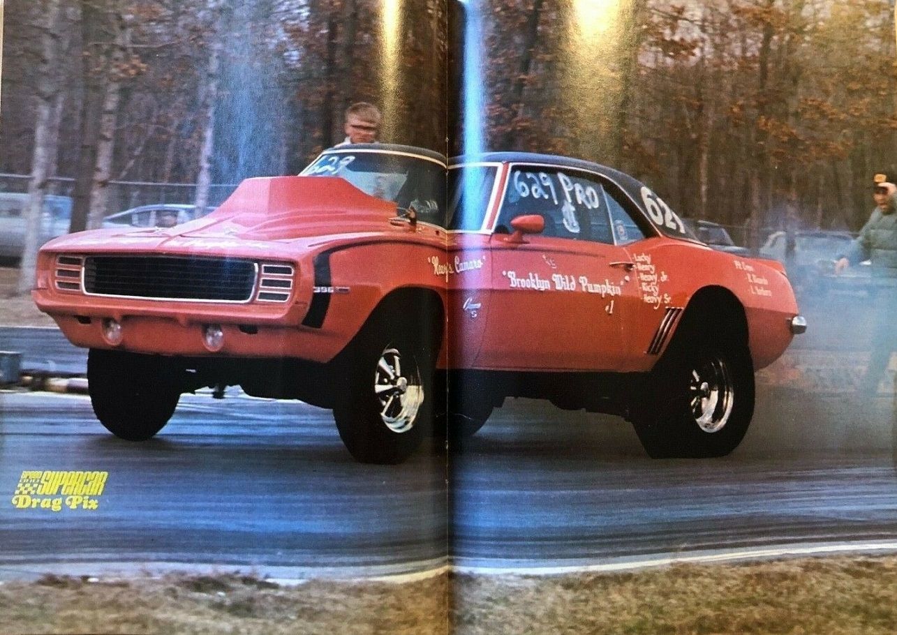 Badass drag racing car spits out exhaust as it peels out. On the side of the car is text reading "Brooklyn Wild Pumpkin."