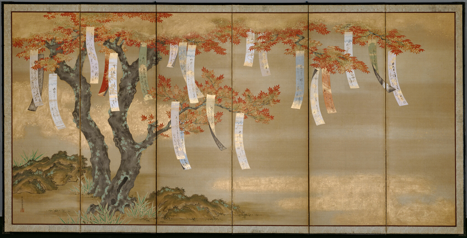 Long strips of paper festoon the branches of a tree in fall foliage.