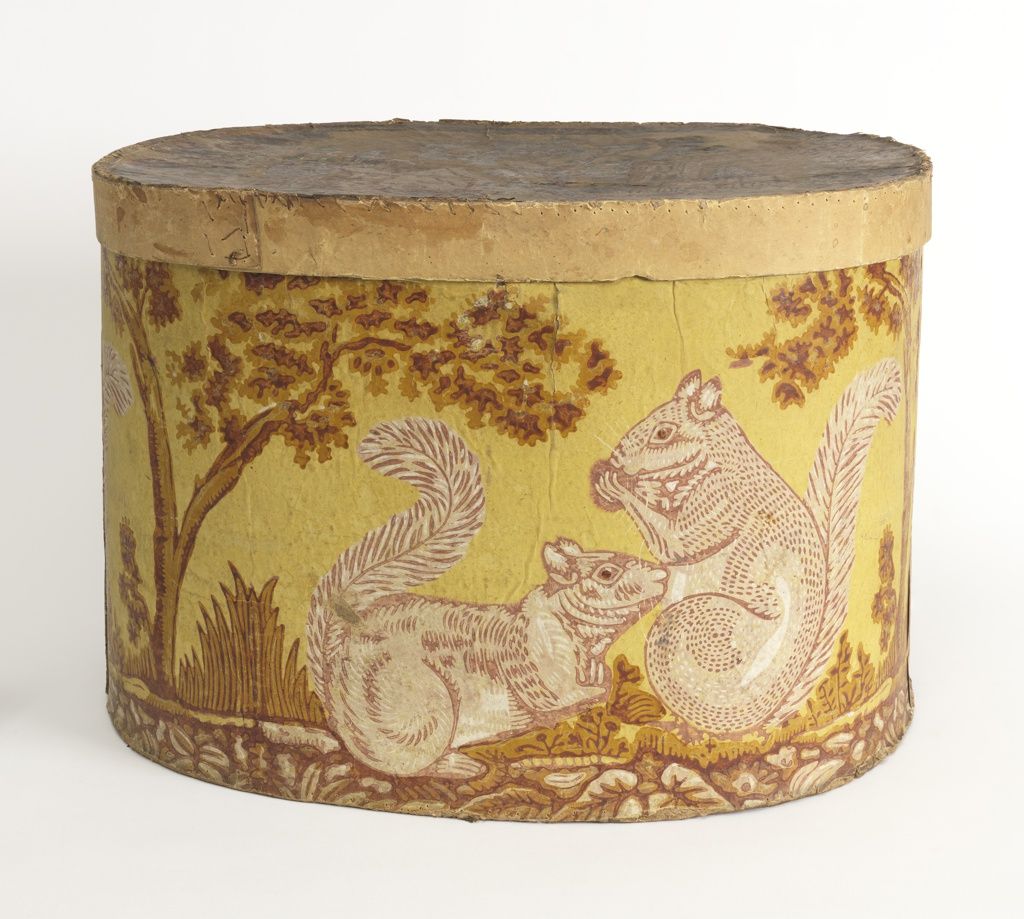 A circular box, decorated with two squirrels. One enjoys a nut, while another looks on with perhaps a pleading look in its eye.